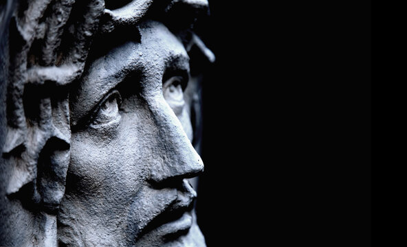 Jesus Christ in profile against dark background. Ancient statue. Copy space. Horizontal image.