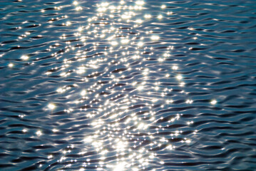 light solid ripples on the sea water of pale blue color with glare from sunlight