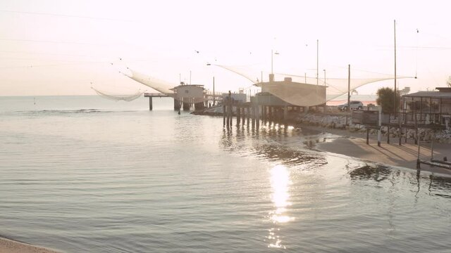 Landscape of fishing huts in the river at sunrise with typical italian fishing machine, called ""trabucco"",Lido di Dante, fiumi uniti Ravenna near Comacchio valley.