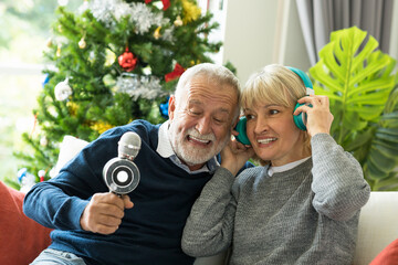 Happy senior couple sing a song and celebrating Christmas day. Cheerful grey haired grandparents at...