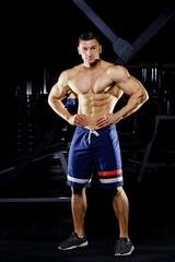 Fototapeta na wymiar Young bodybuilder with great muscles posing in gym
