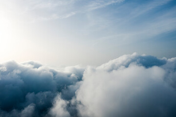 View from above, drone point of view, stunning aerial shot of some fluffy clouds with a bright sun.