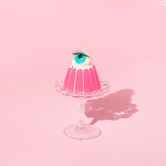Creative layout with pink jelly on dish with eyeball figurine on pastel pink background. Halloween...
