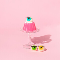 Creative layout with pink jelly on dish with eyeball figurines on pastel pink background. Halloween...