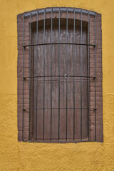 Mustard yellow facade window and antique wood door