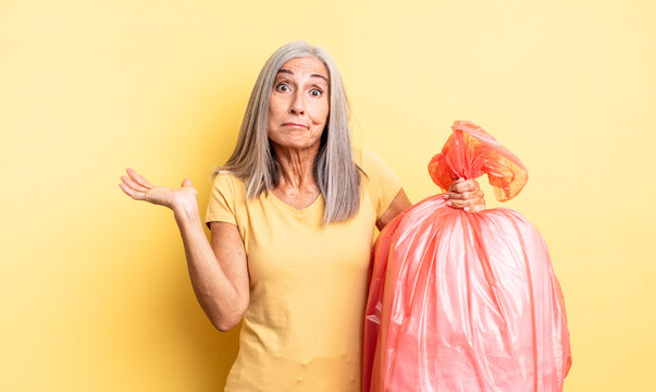 middle age pretty woman feeling puzzled and confused and doubting. plastic garbaje bag