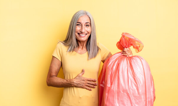 middle age pretty woman laughing out loud at some hilarious joke. plastic garbaje bag