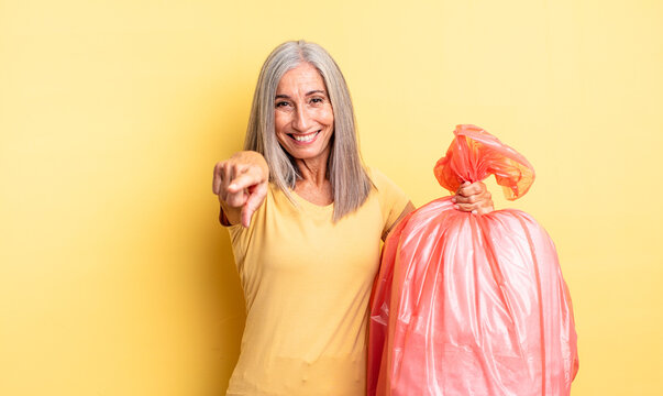 middle age pretty woman pointing at camera choosing you. plastic garbaje bag
