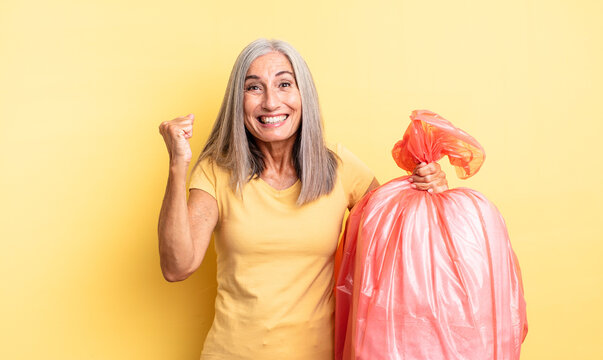 middle age pretty woman feeling shocked,laughing and celebrating success. plastic garbaje bag