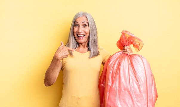 middle age pretty woman feeling happy and pointing to self with an excited. plastic garbaje bag