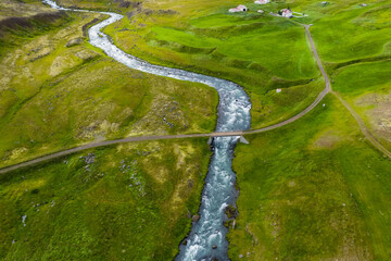 Iceland. Aerial view of road and small bridge over blue mountain river. Aerial scenic view of Iceland landscape. Travel vacation concept