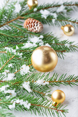 Fir branches decorated with golden Christmas balls and cones on a light background. Christmas and New Year concept.