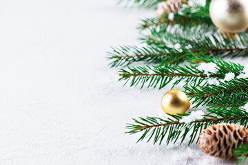 Fir branches decorated with golden Christmas balls and cones on a light background. Christmas and New Year concept. Horizontal orientation, copy space. 