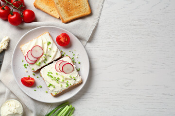 Toasted bread with cream cheese and vegetables on white wooden table, flat lay. Space for text