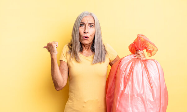 middle age pretty woman looking astonished in disbelief. plastic garbaje bag