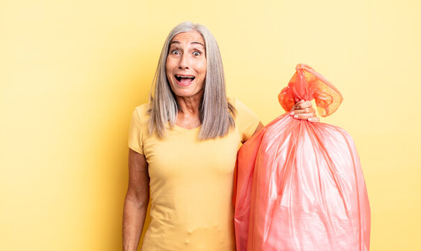 middle age pretty woman looking happy and pleasantly surprised. plastic garbaje bag