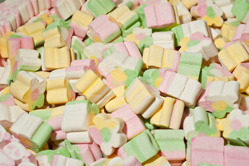 Texture of yellow, white, green and pink candies. Sweets on a pile close up. Sweets shop window.
