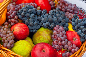 Apples, pears, grapes and peppers in a basket. Vegetables close up. Picnic food.