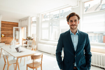 Male professional with hands in pockets standing at office
