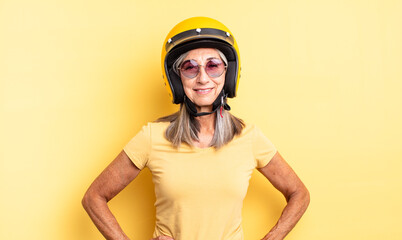 middle age pretty woman smiling happily with a hand on hip and confident. motorbike helmet concept