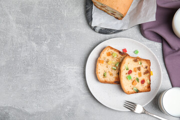 Delicious cake with candied fruits and milk on light grey table, flat lay. Space for text