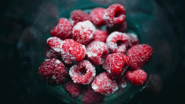 A pile of frozen raspberries is quickly frosting in a glass. Healthy food. 4K timelapse