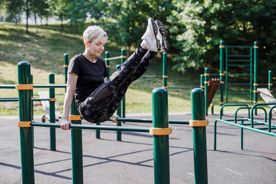 Woman balancing with feet up on exercise equipment at park