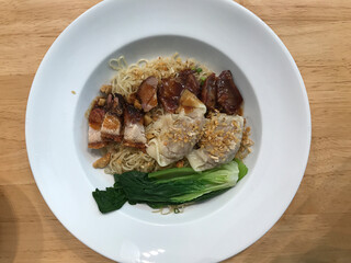 Thai egg noodles topped with pork wontons,  roasted red pork and crispy pork.