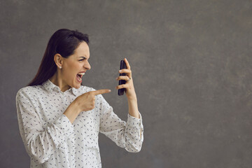 Angry aggressive woman nervously screaming looking with hatred at mobile phone screen. Portrait of...