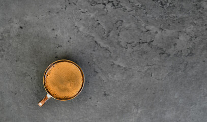 Cup of coffee on a gray stone background. Top view with copy space. Strong ristretto or espresso with frothy coffee