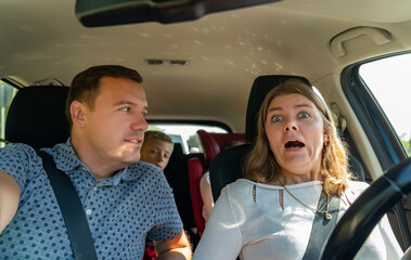 Front portrait of scared woman driving car and happy man. Shock reaction. Driver scream in fear...