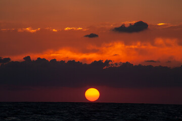 Sunset with huge sun falling on the sea at Aphrodite beach in Cyprus