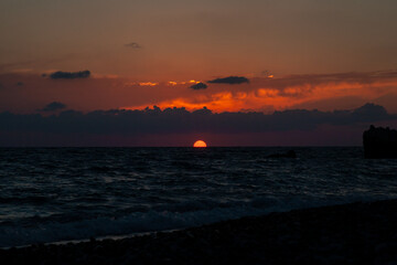 Fototapeta premium Sunset with huge sun falling on the sea at Aphrodite beach in Cyprus