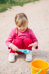 girl playing with a blue shovel siting on the floor