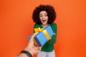 Portrait of happy excited woman with Afro hairstyle wearing green casual style sweater getting blue...
