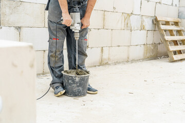 young male bricklayer builder kneads concrete, for laying aerated concrete blocks, using a...