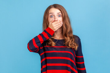Don't tell! Portrait of frightened woman in striped casual sweater covering mouth with hand scared...