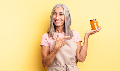middle age pretty woman smiling cheerfully, feeling happy and pointing to the side. peach jam