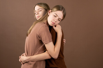 Affectionate twin girls in shirts standing in embrace in front of camera