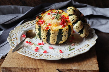 Pumpkin risotto served in a hollowed pumpkin. Baked pumpkin with cheese and pomegranate seeds on...