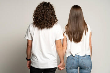 Curly man and long hair woman holding hands, back view, isolated on white.