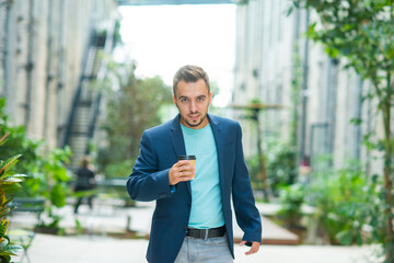 A young successful businessman is working outdoor using smartphone. Man in a casual wear. Business, freelance and remote work.