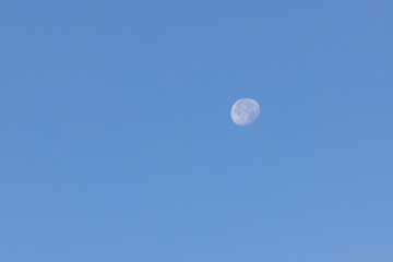 A scenic beautiful day view of a Waxing gibbous moon on a majestic blue sky 