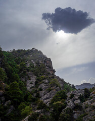 Photograph of a beautiful and majestic landscape in which a large cloud lets some rays of sunlight pass towards the top of that great mountain.