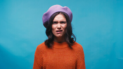 displeased woman grimacing and feeling disgusted isolated on blue