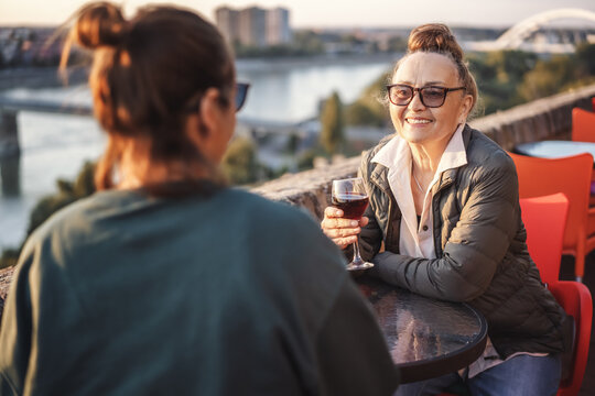 Happy Beautiful Mature Woman In Glasses 60 Years Old Sitting In A Cafe With Her Girlfriend Drinking Wine