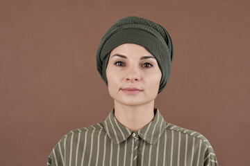 Horizontal close-up studio portrait of attractive Muslim woman wearing fashionable striped shirt...