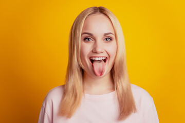 Portrait of funny funky adorable lady protrude tongue on yellow background