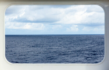 View of the sea and sky from a rectangular ship window.