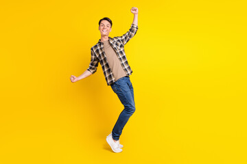 Fototapeta na wymiar Photo of astonished positive guy celebrate victory wear plaid shirt jeans shoes isolated yellow color background